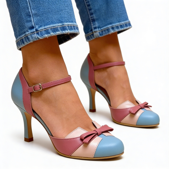 Womens retro bow accent Mary Jane pumps featuring a rounded toe, ankle strap fastening, contrast colour block panels and slim heel design